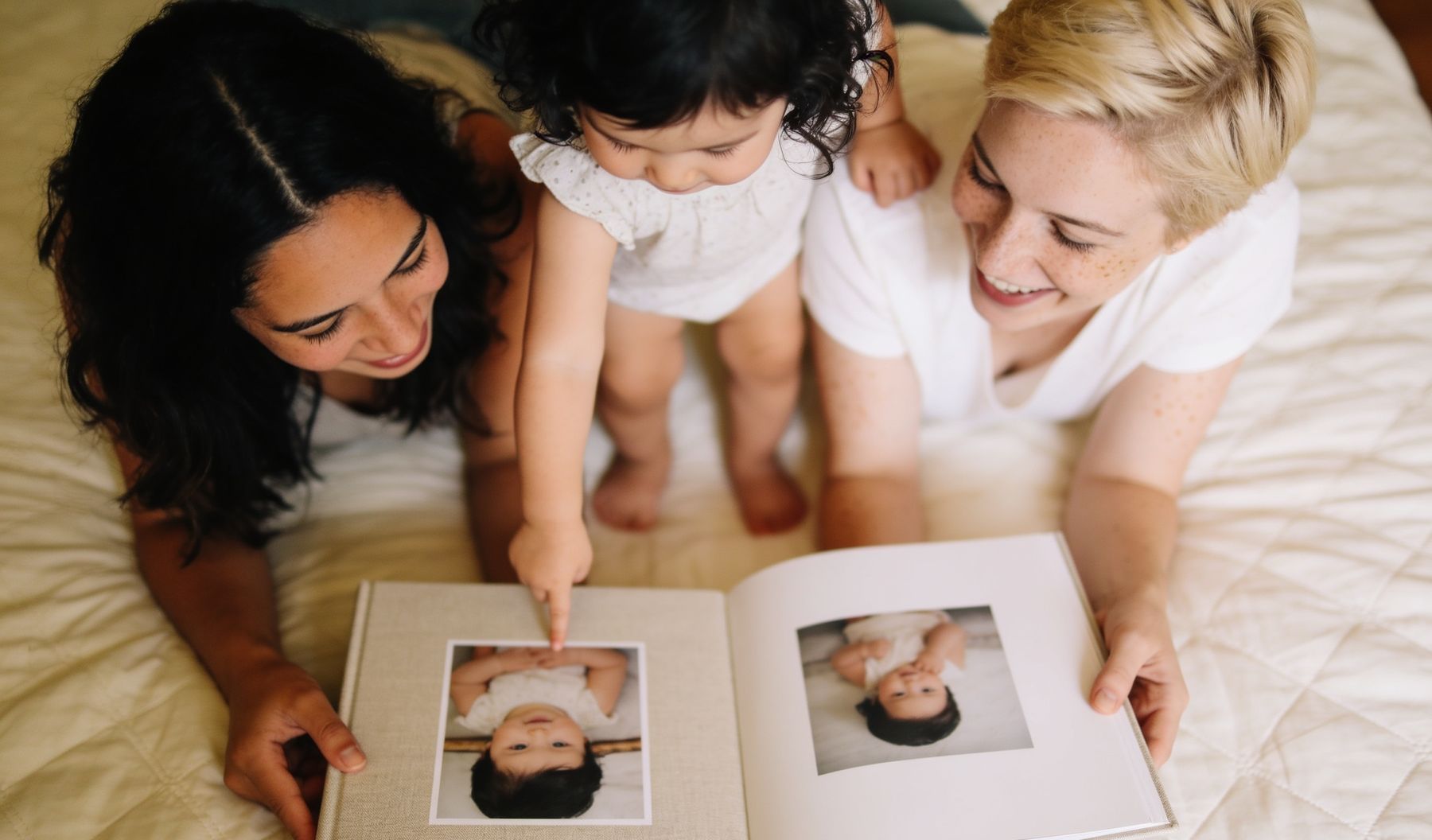 The baby book open on a bed, a hand turning a page